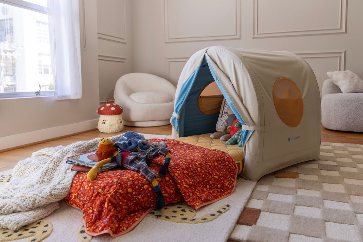 Starhaven Bed set up in a cozy bedroom with the red patterned blanket, toys, and books spread out in front